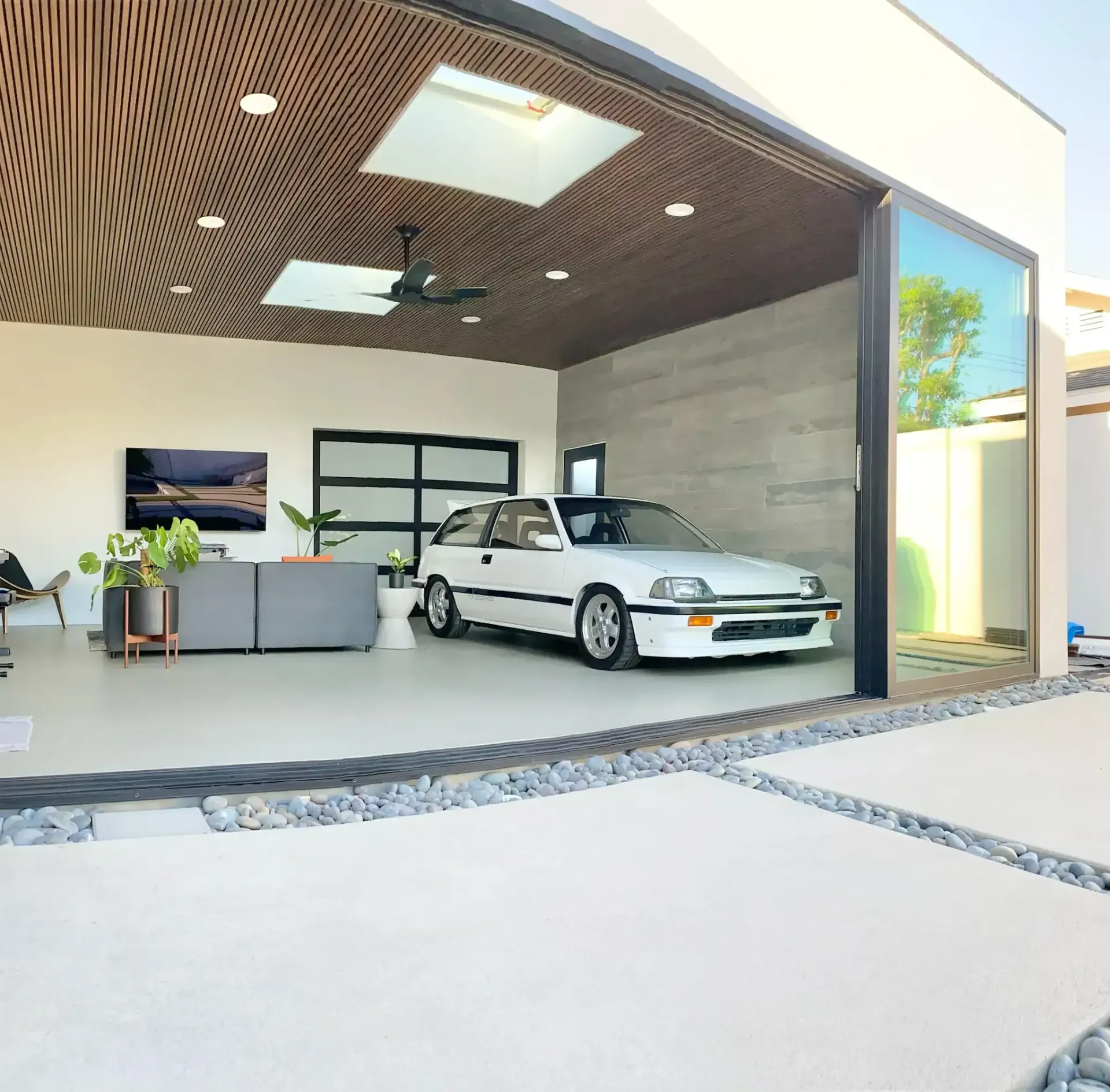 A white car is parked in a garage with the doors open