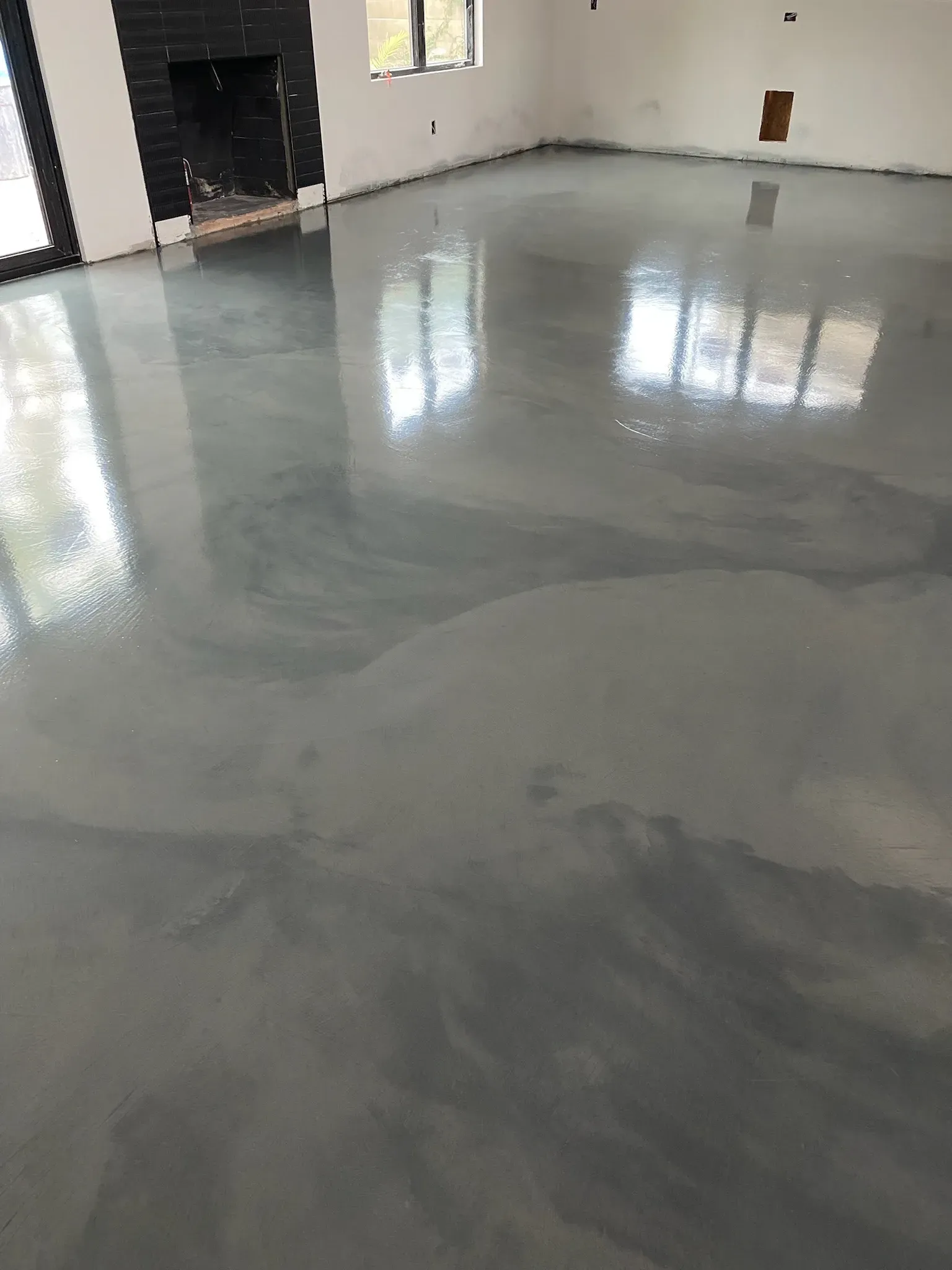 A living room with a shiny concrete floor and a fireplace.