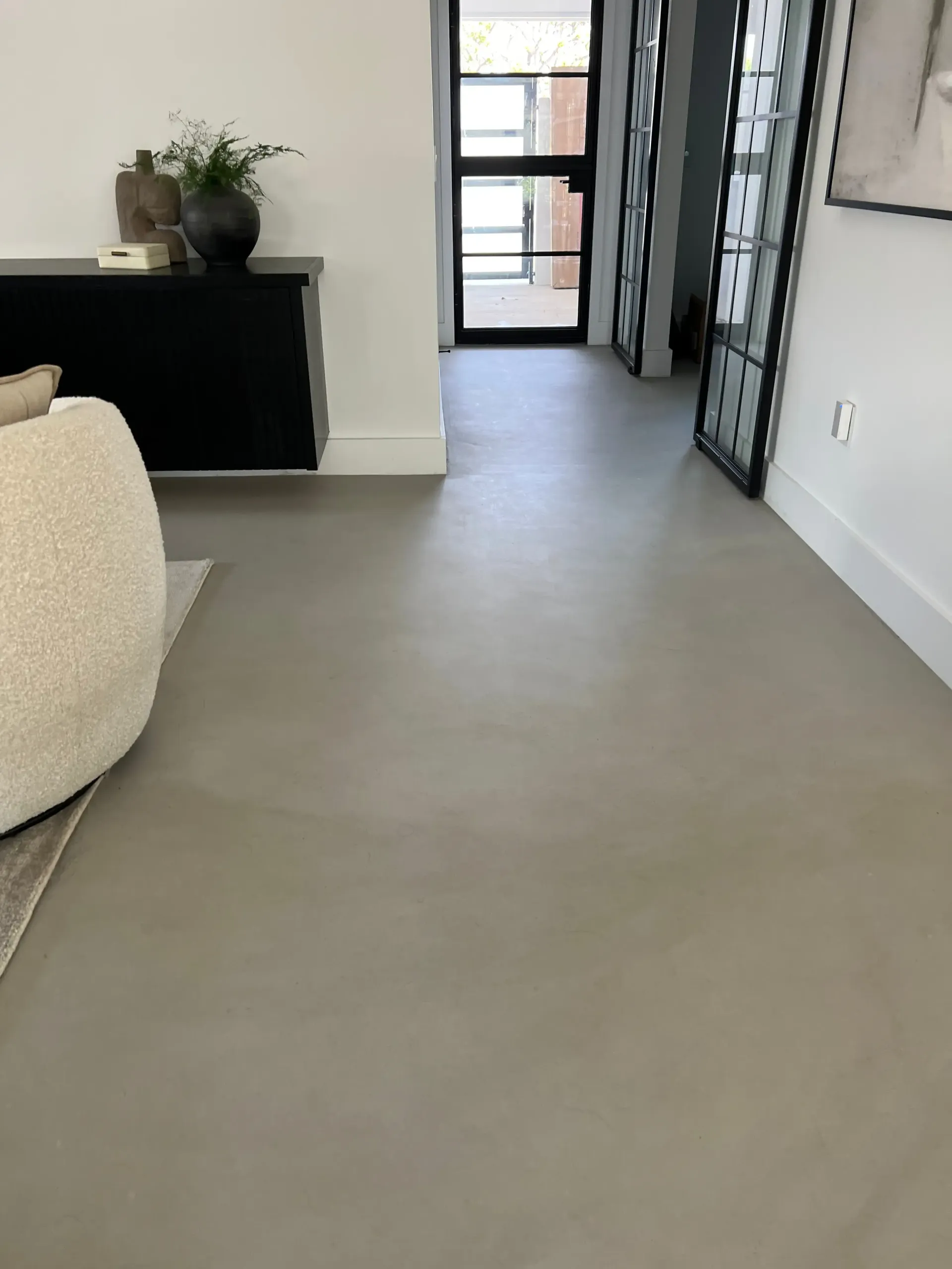 A living room with a gray floor and a white couch.