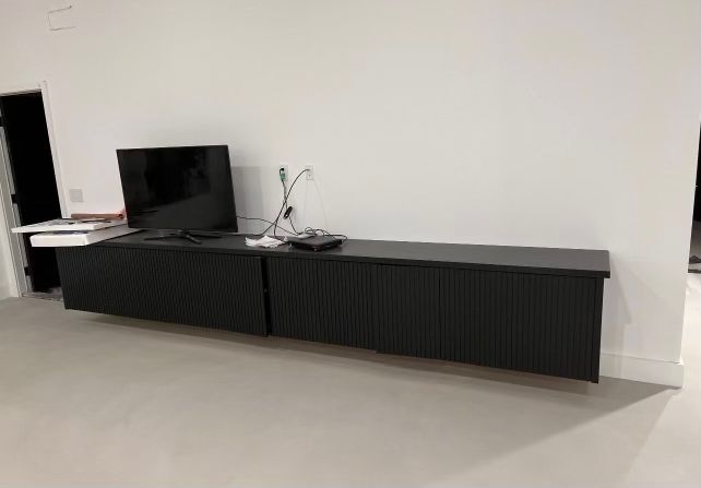 A living room with a long black entertainment center and a flat screen tv.