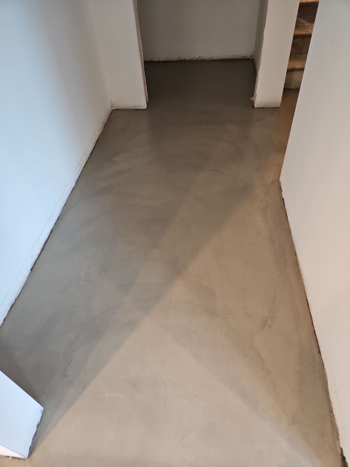 A hallway with a concrete floor and white walls.