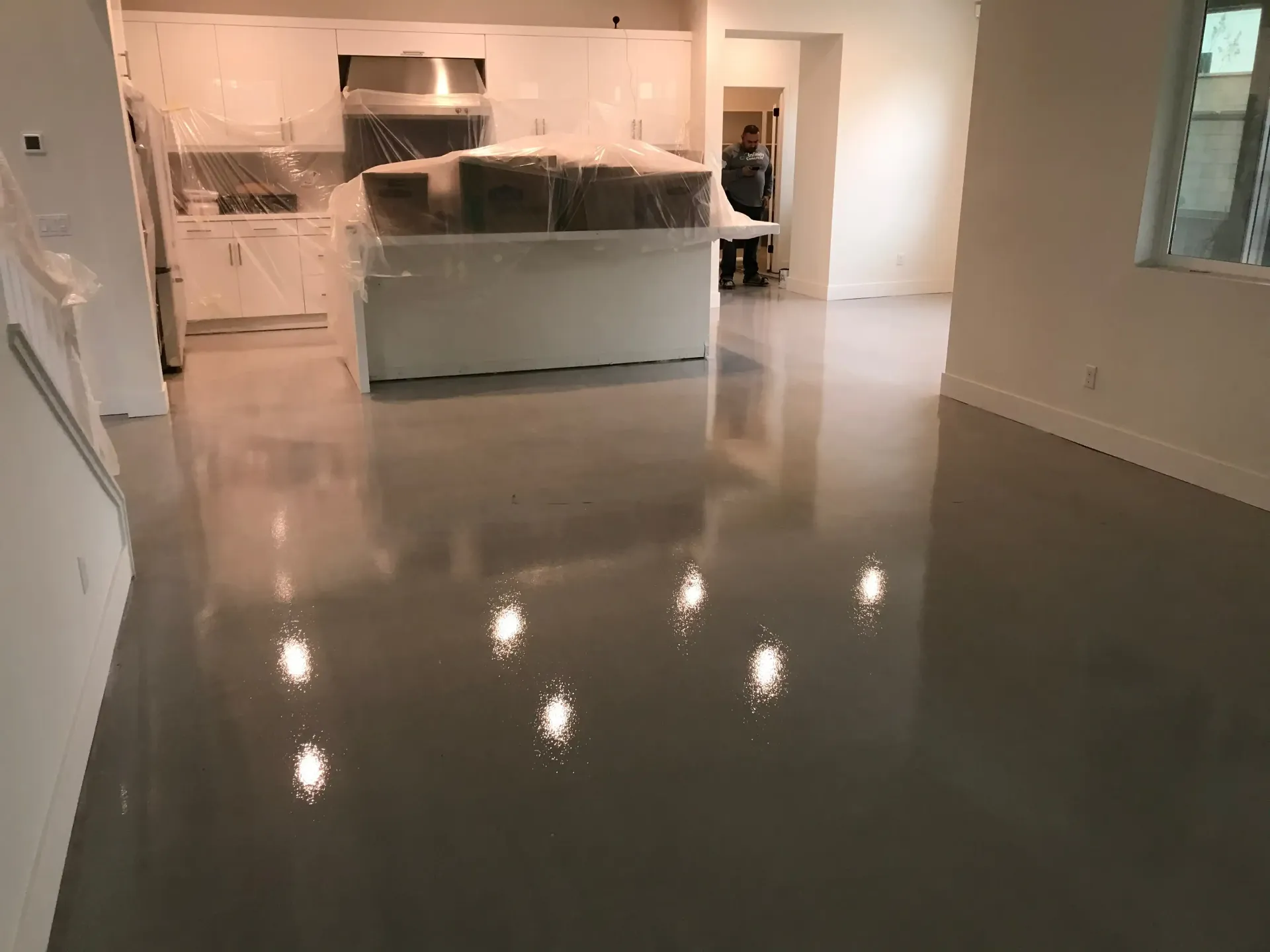 A living room with a shiny floor and a kitchen in the background.