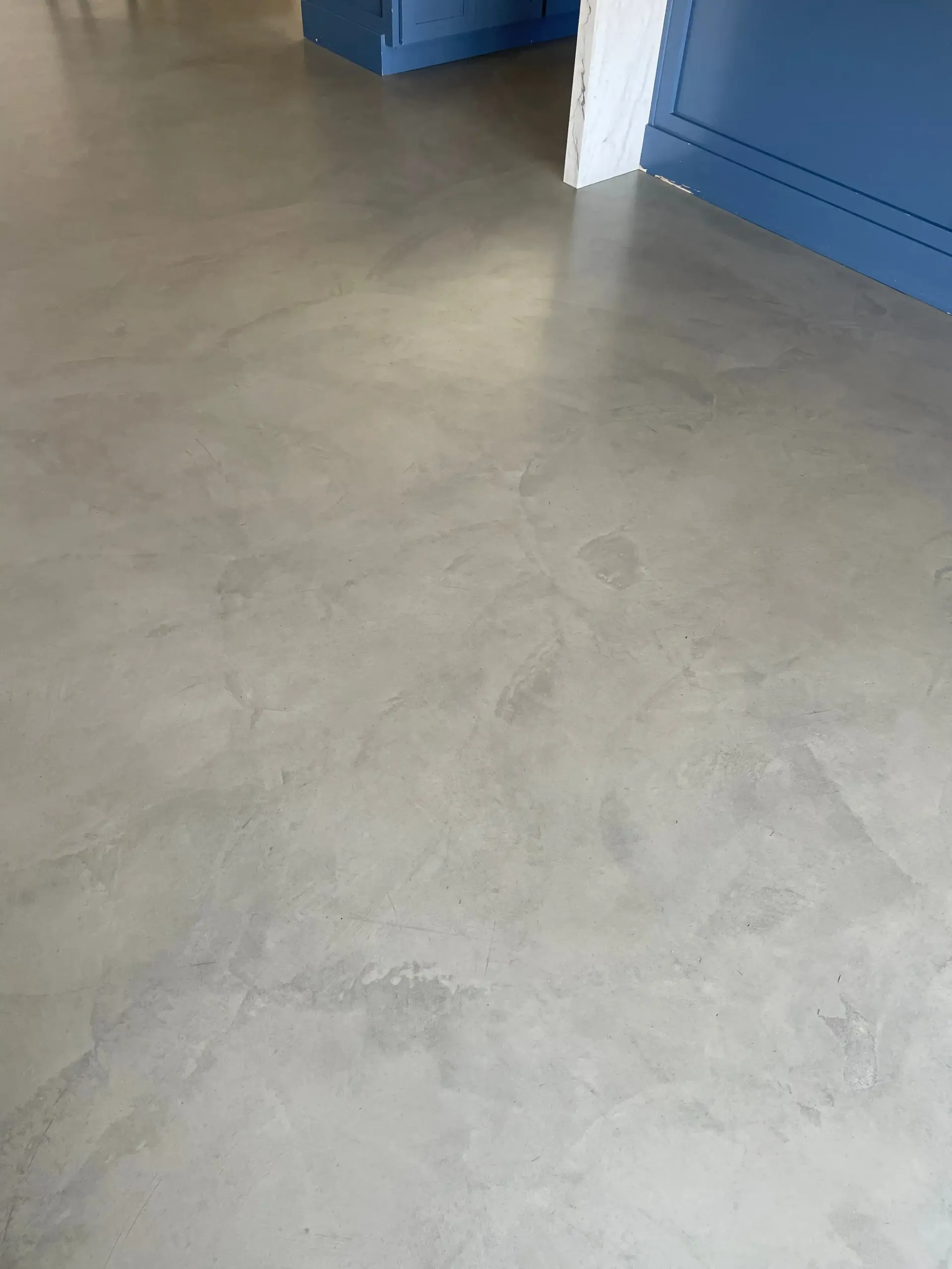 A close up of a concrete floor in a room with a blue wall.