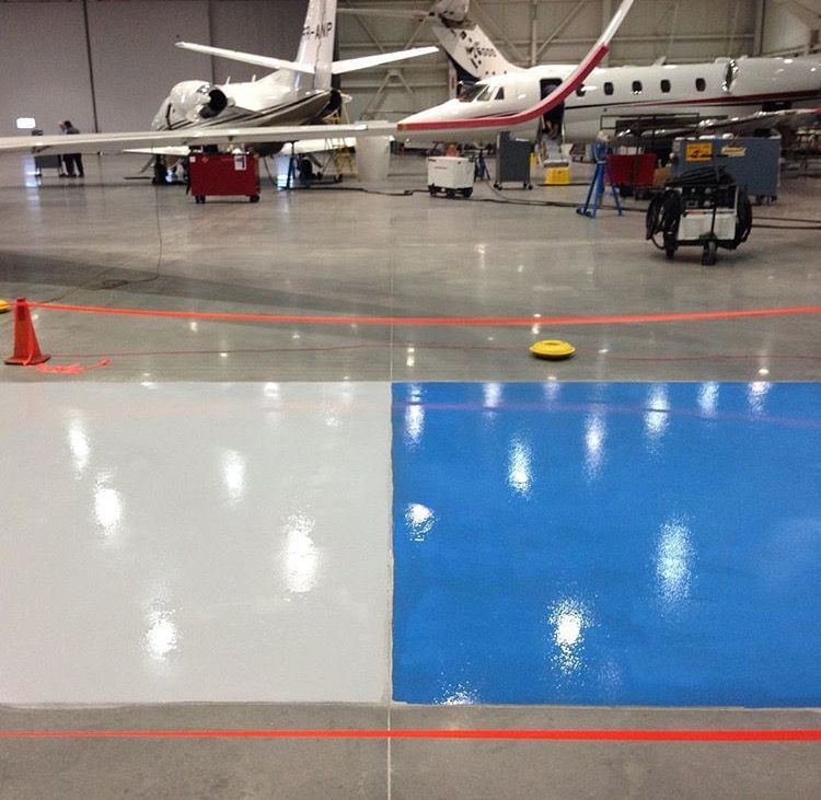 Two airplanes are parked in a hangar with a blue floor
