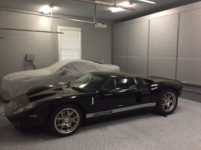 A black sports car is parked in a garage with other cars
