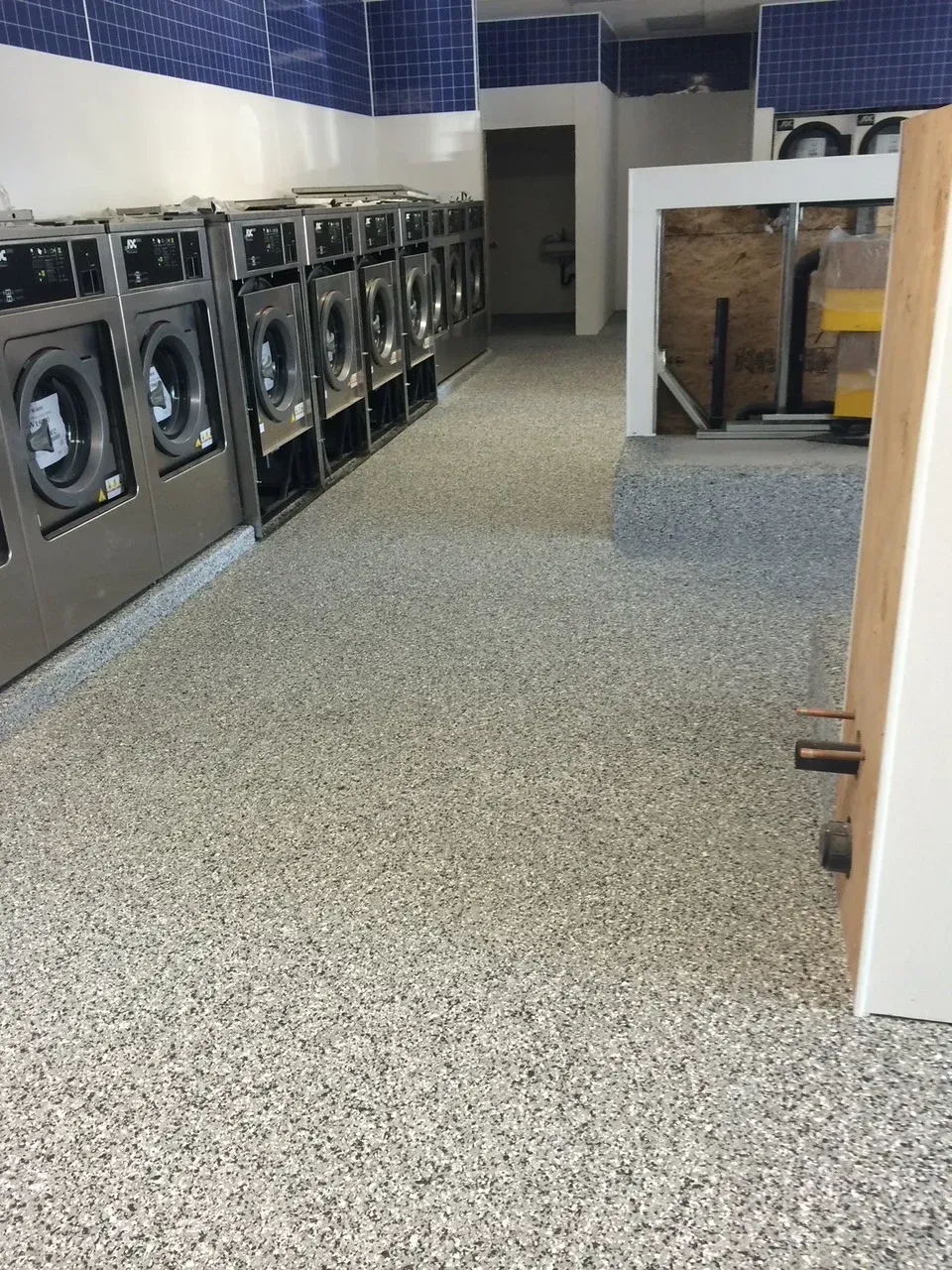 A row of washing machines are lined up in a laundromat.