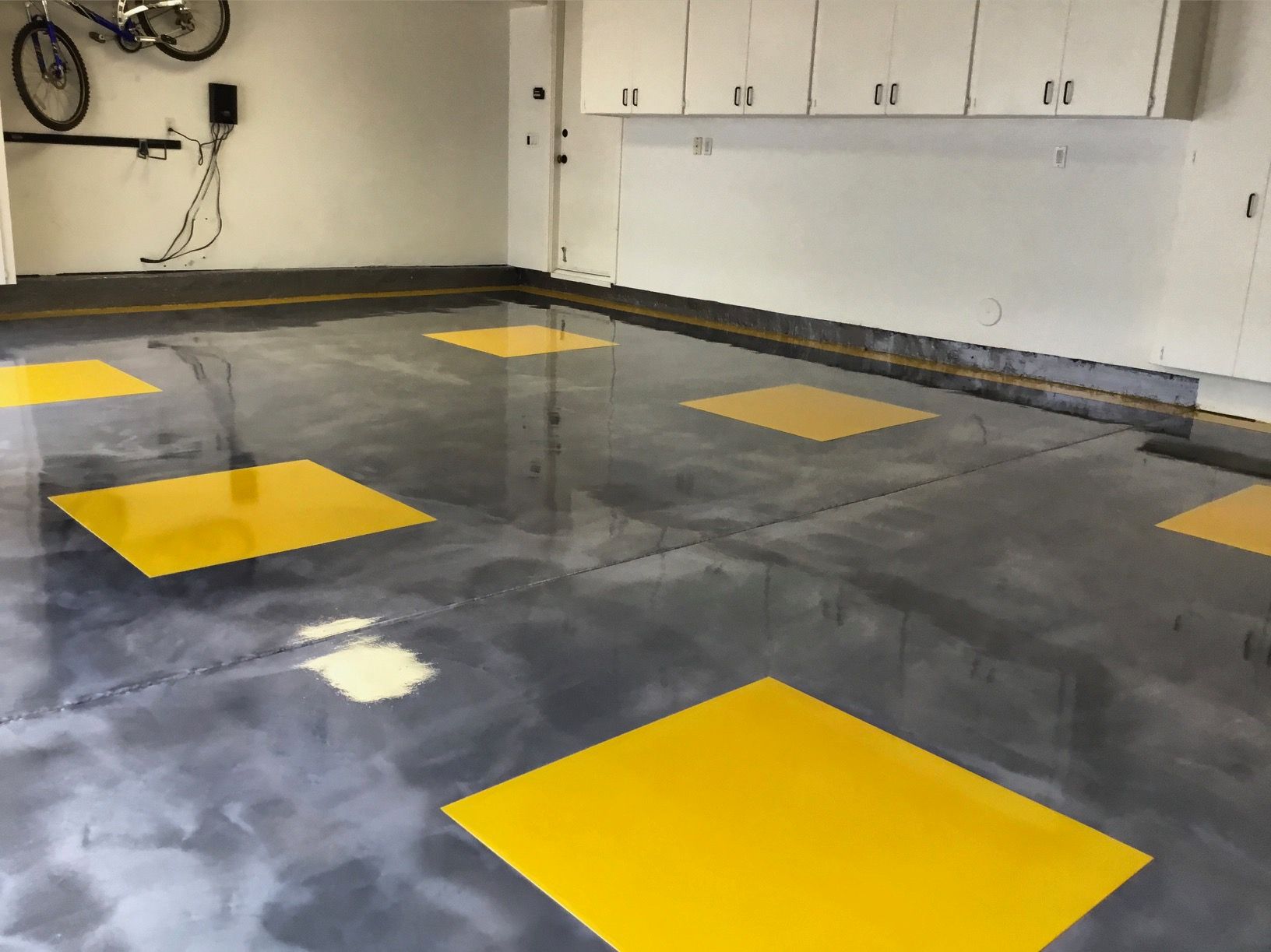 A garage with a gray floor and yellow squares on it.