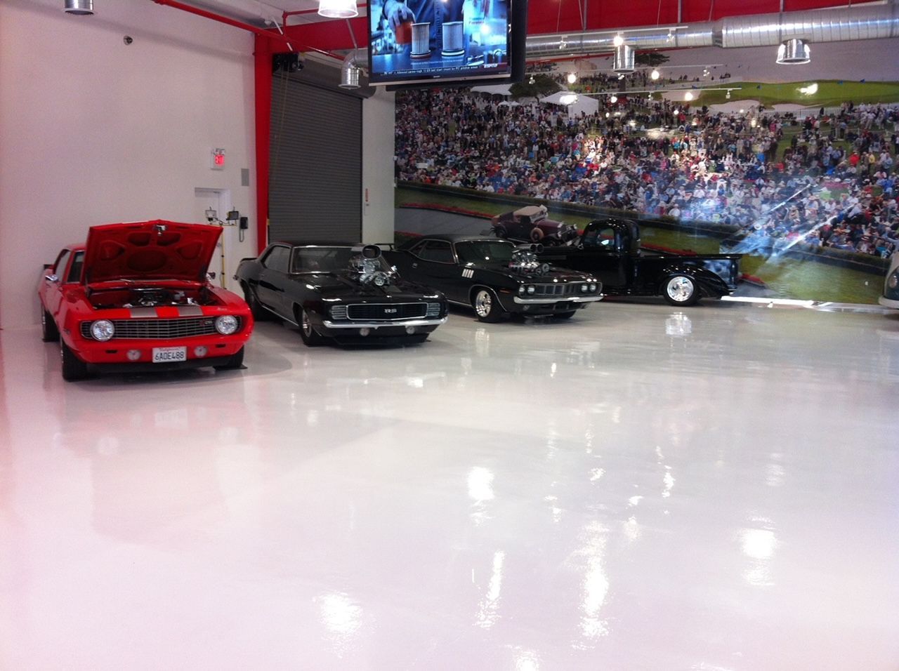 A red car is parked in a garage with other cars