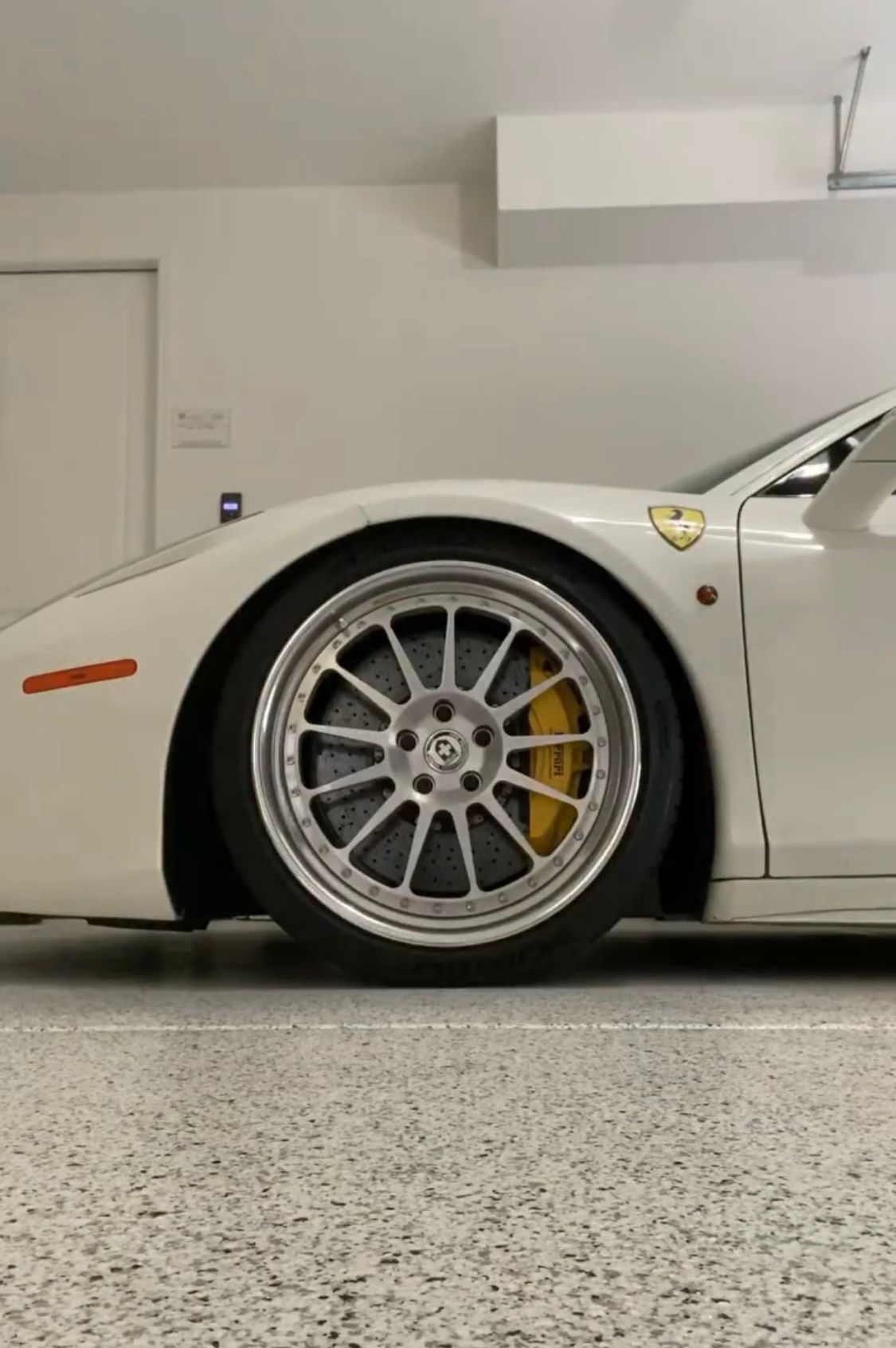 A white sports car is parked in a garage.