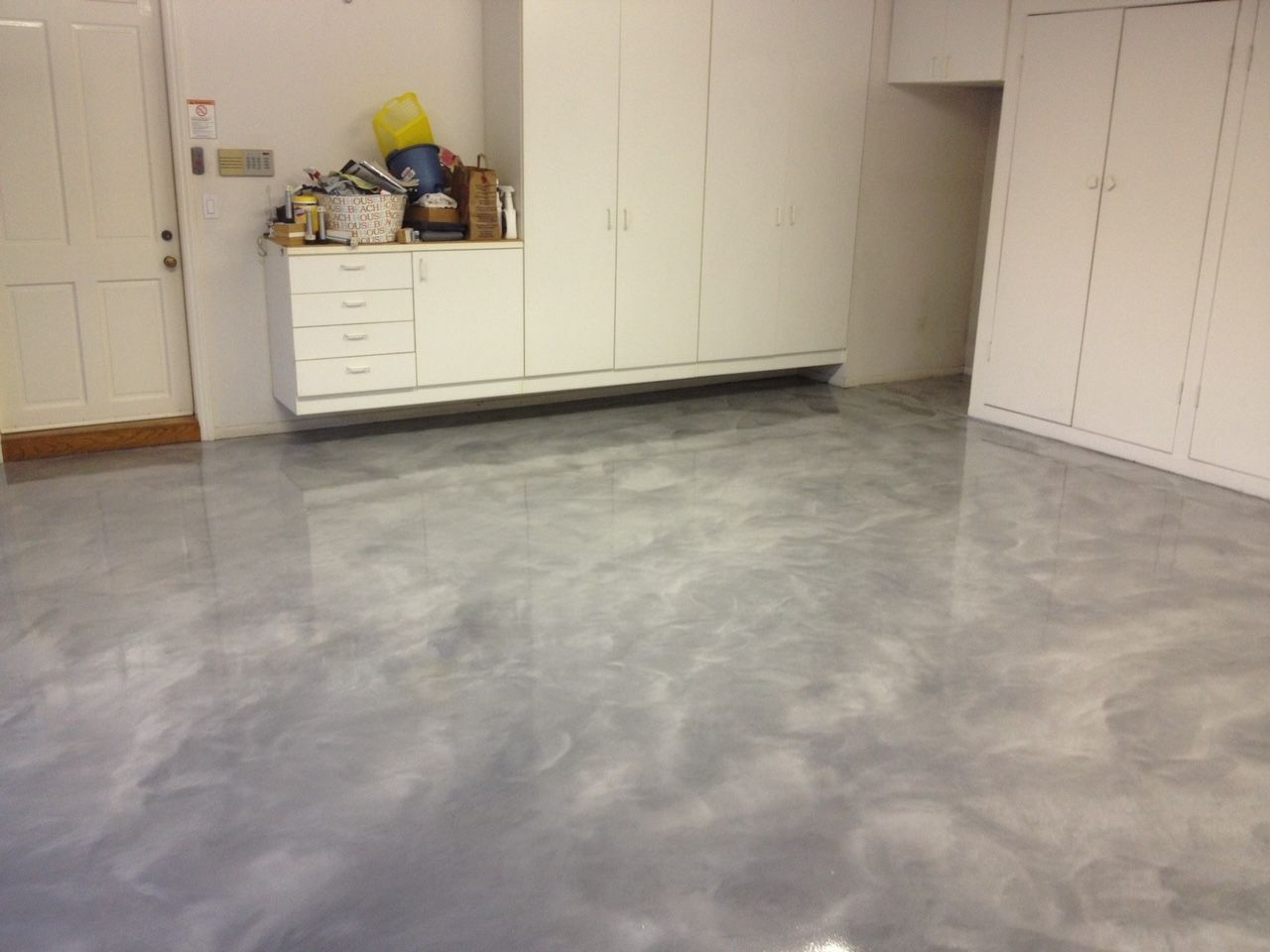 A room with a gray floor and white cabinets