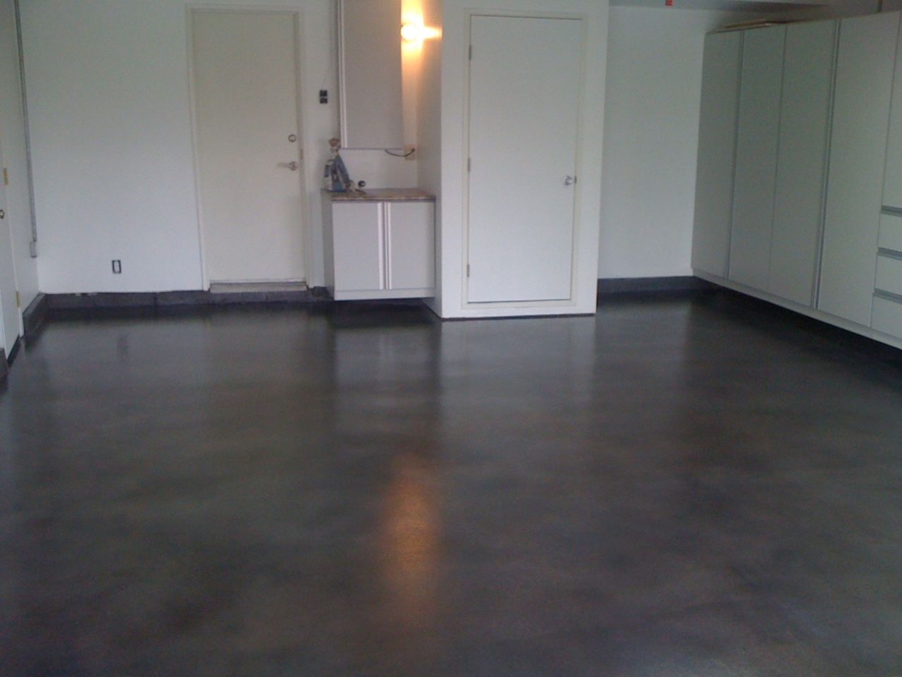 An empty room with a black floor and white cabinets