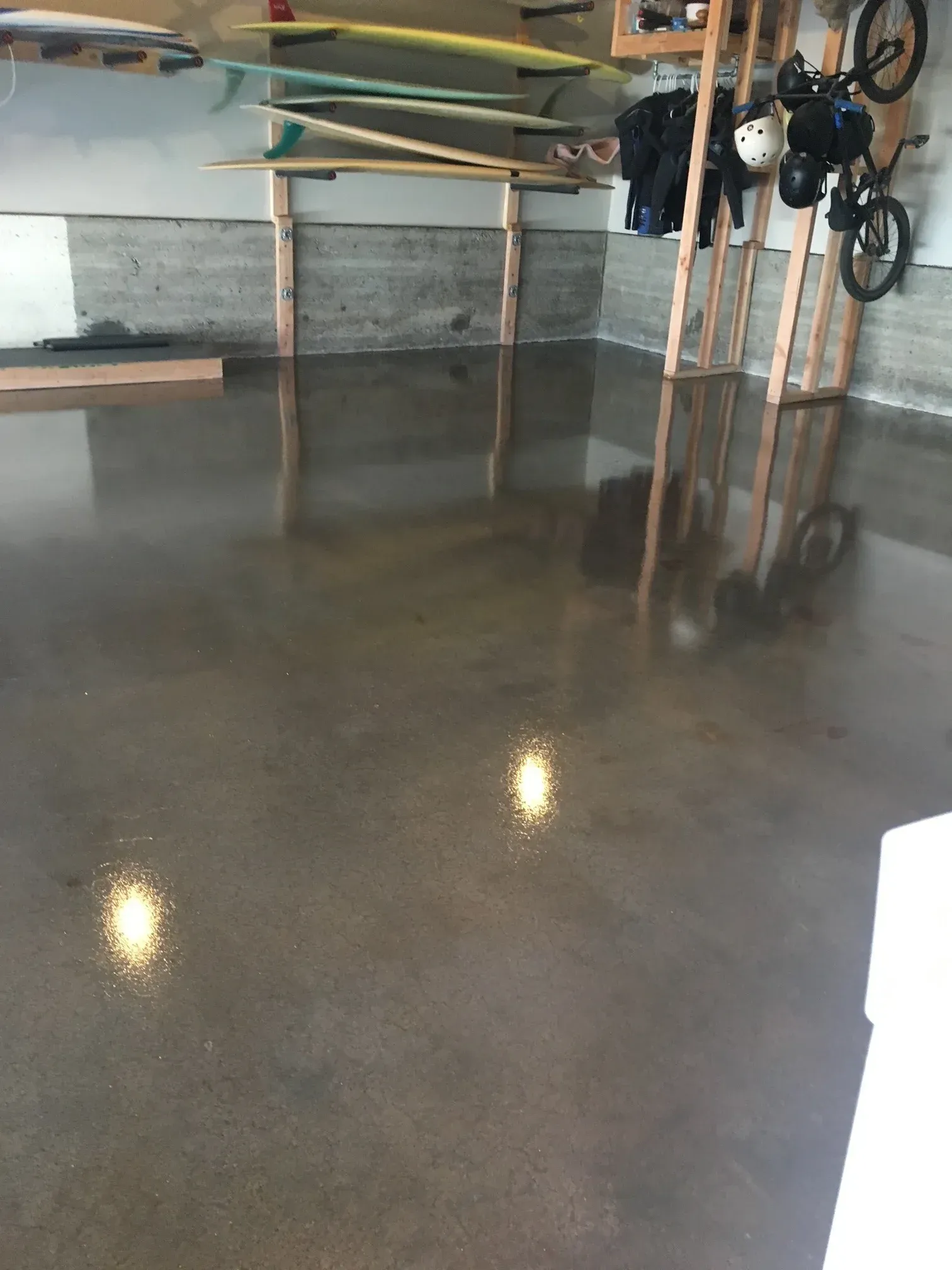 A concrete floor in a garage with surfboards and a bike