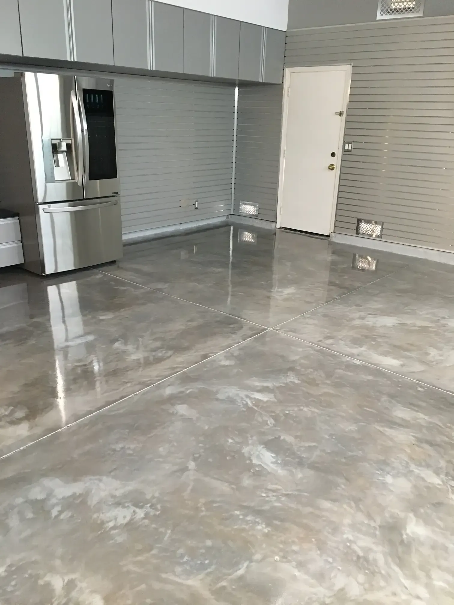 A kitchen with a stainless steel refrigerator and a marble floor.