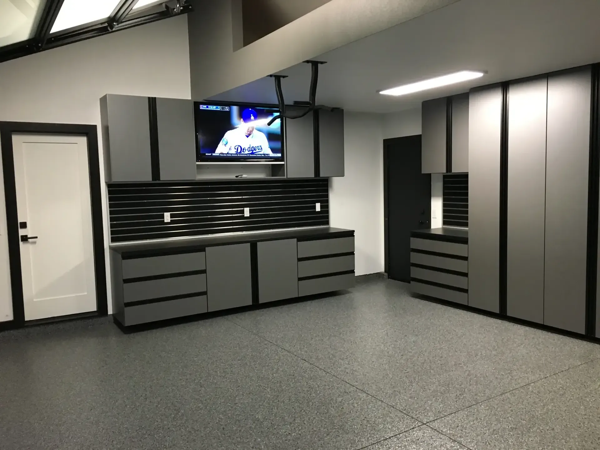 A garage with lots of cabinets and a flat screen tv on the wall.
