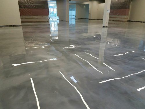 A shiny concrete floor in a building with white lines on it.
