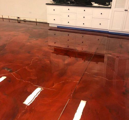 A kitchen with a red floor and white cabinets