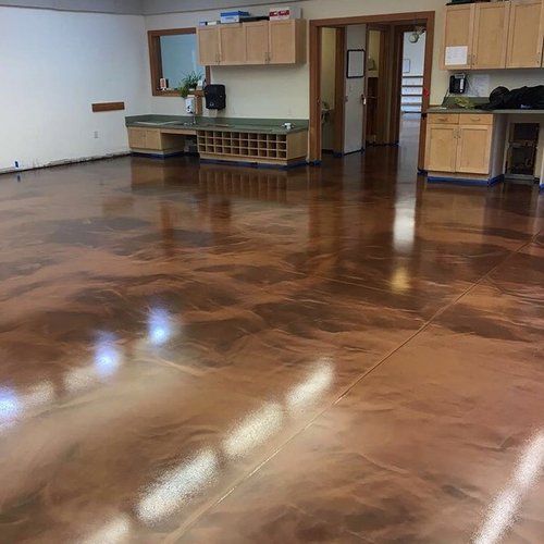 A large room with a stained concrete floor and wooden cabinets.