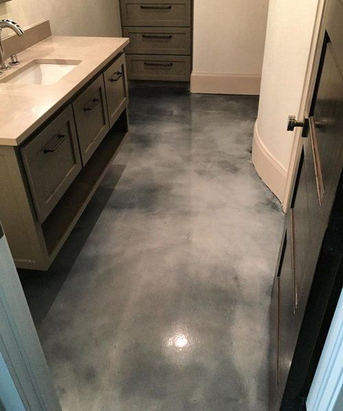 A bathroom with a sink , cabinets and a concrete floor.