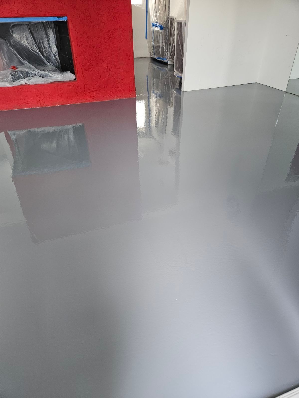 A living room with a gray floor and a red fireplace.