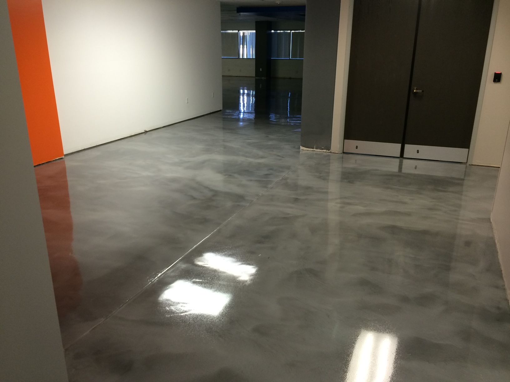 A hallway with a shiny concrete floor and a door.