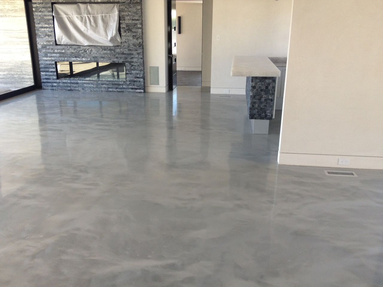 A living room with a concrete floor and a fireplace