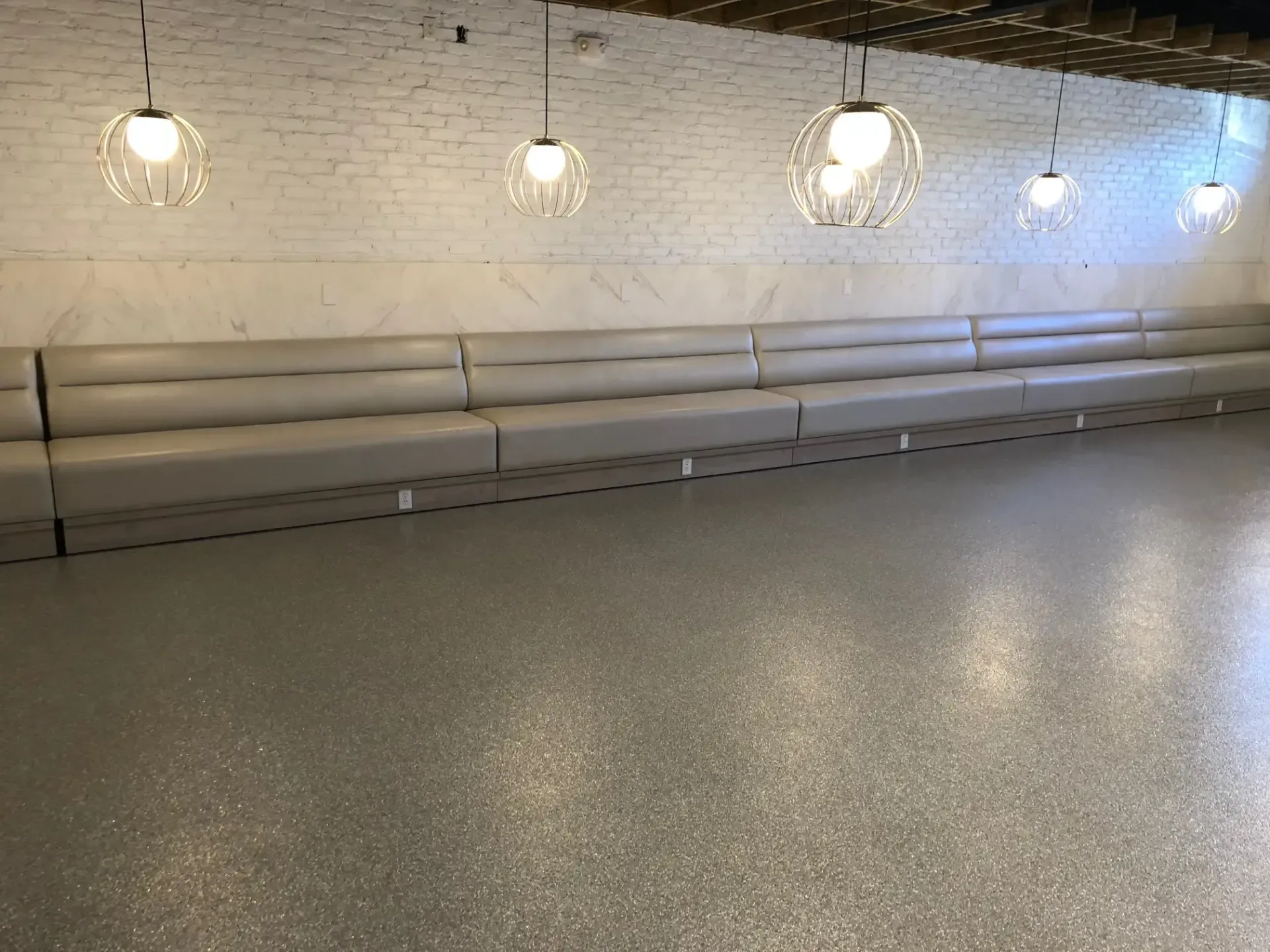 A large room with a long couch and a concrete floor.