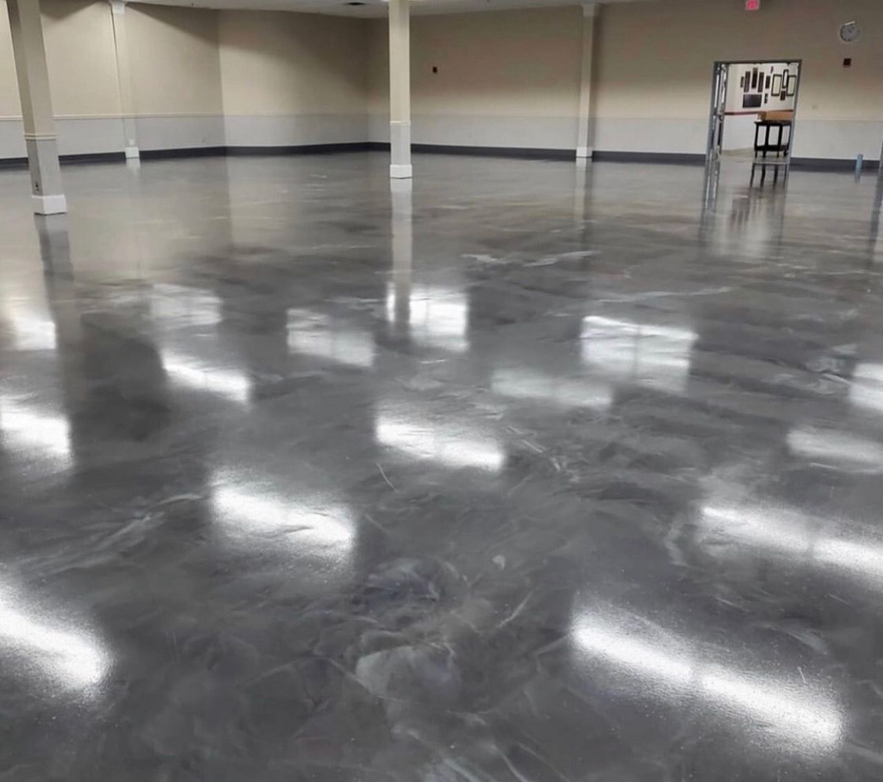 A large room with a shiny metallic floor and a reflection of lights.