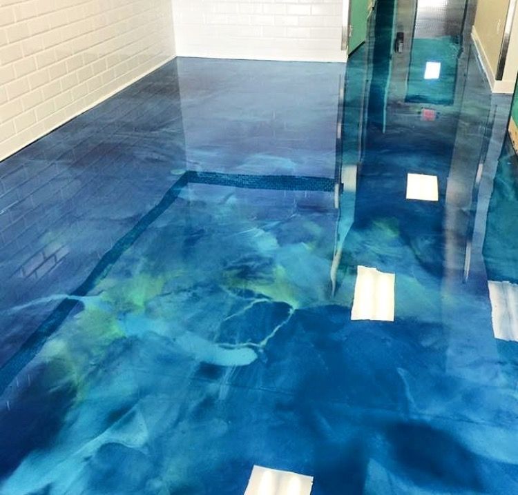 A blue metallic floor in a room with white brick walls.