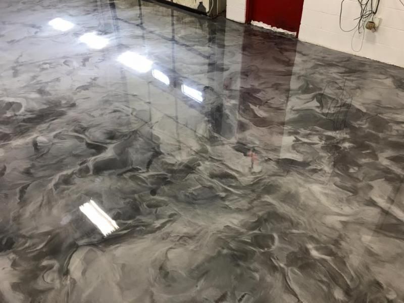 A shiny metallic floor in a room with a red door.