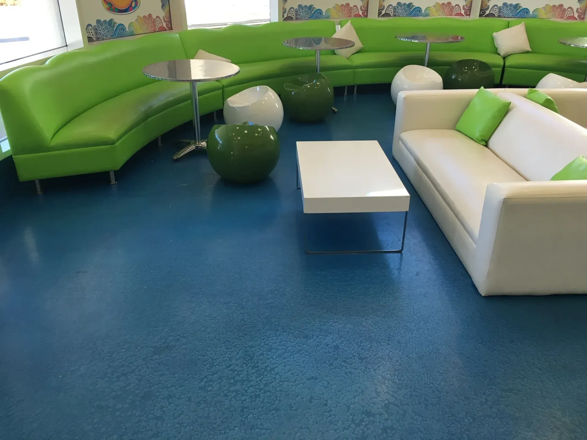 A living room with green and white furniture and a blue floor