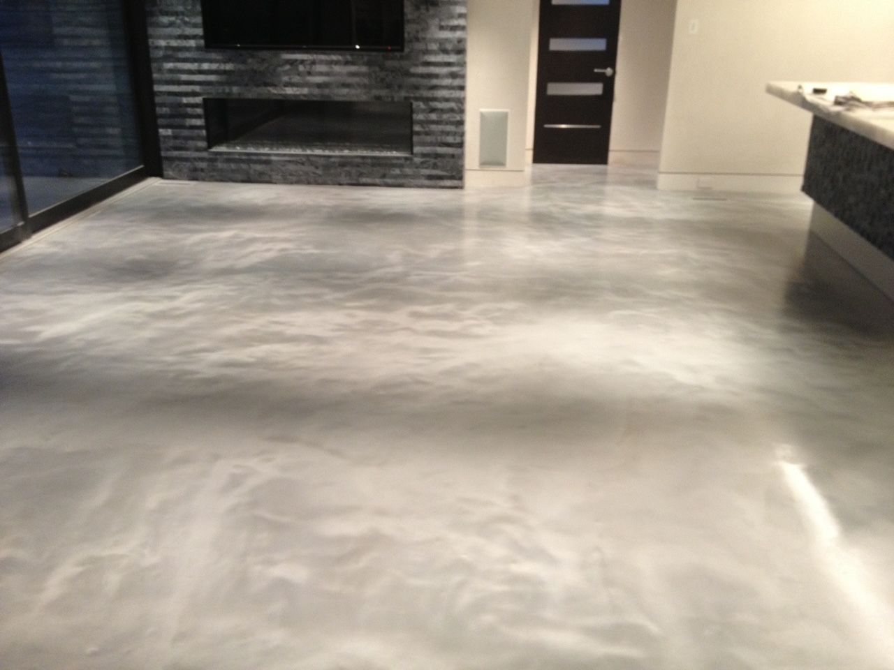 A living room with a concrete floor and a fireplace.