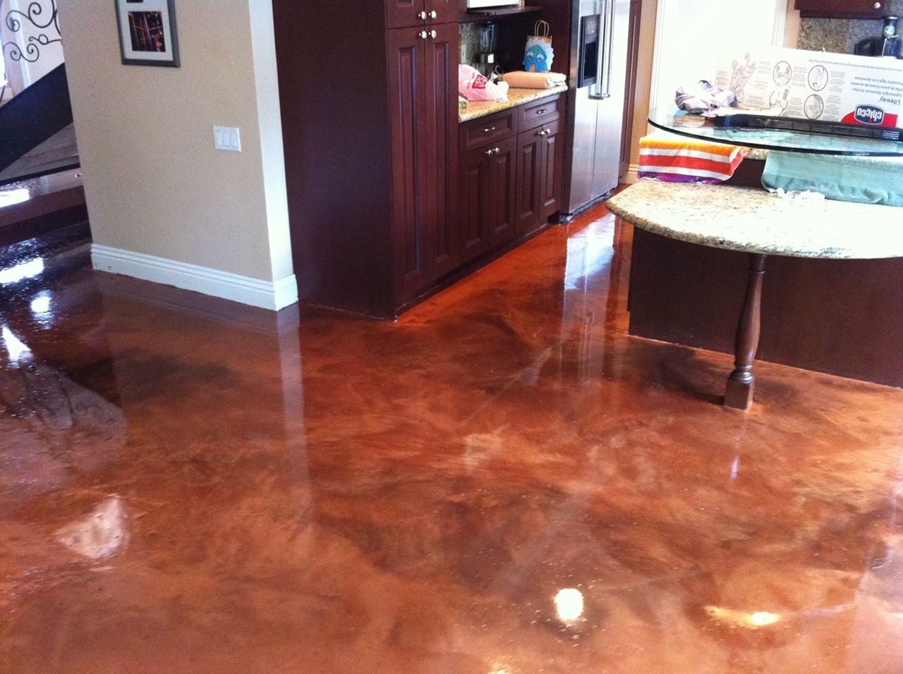 A kitchen with a shiny concrete floor and a table