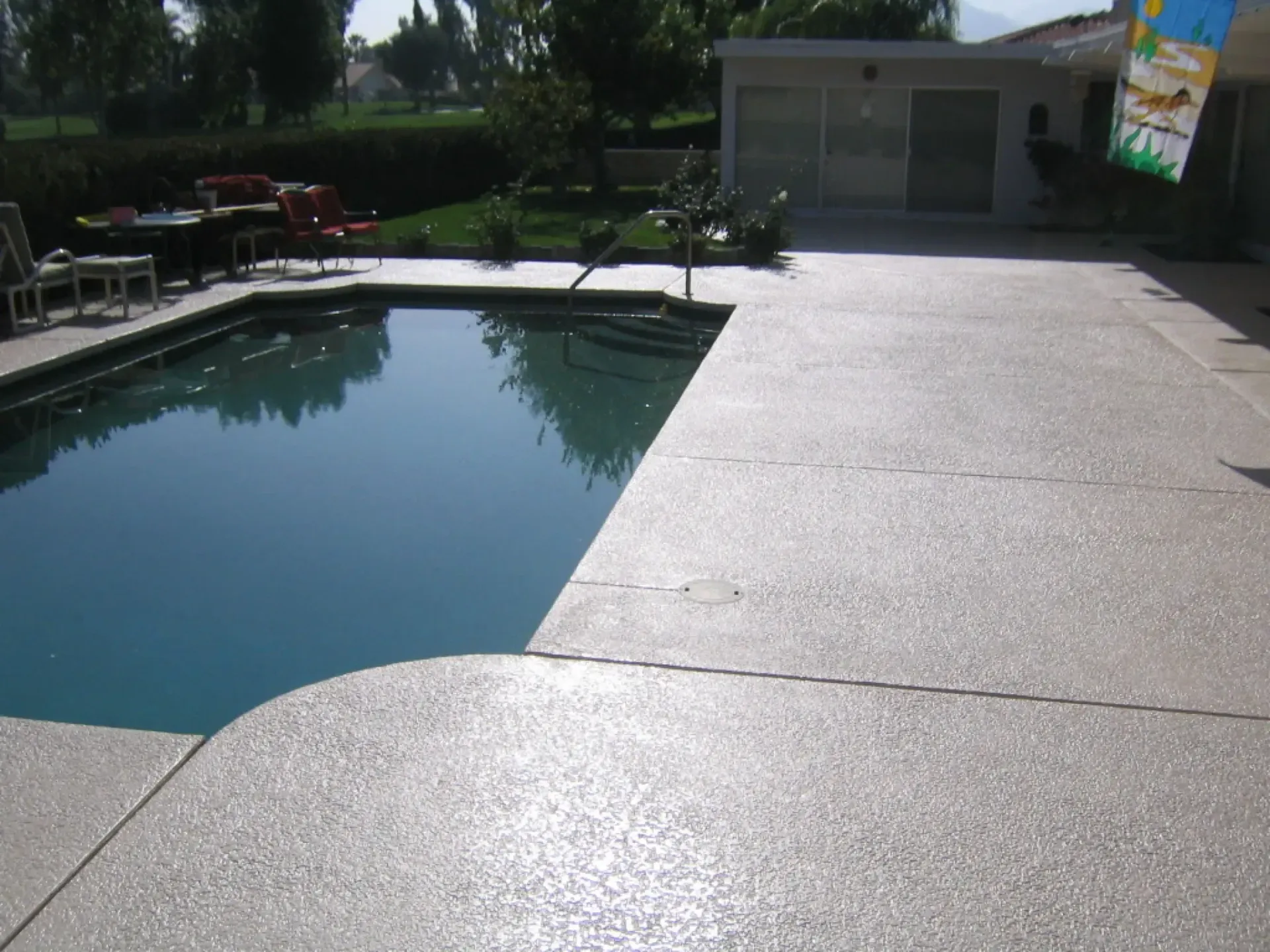 A large swimming pool is surrounded by a concrete deck