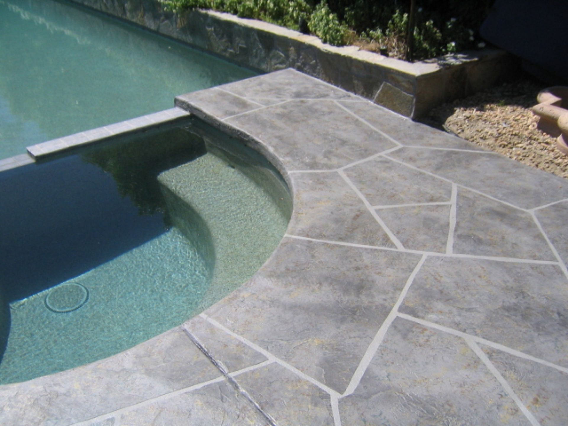 A swimming pool with a concrete walkway leading to it