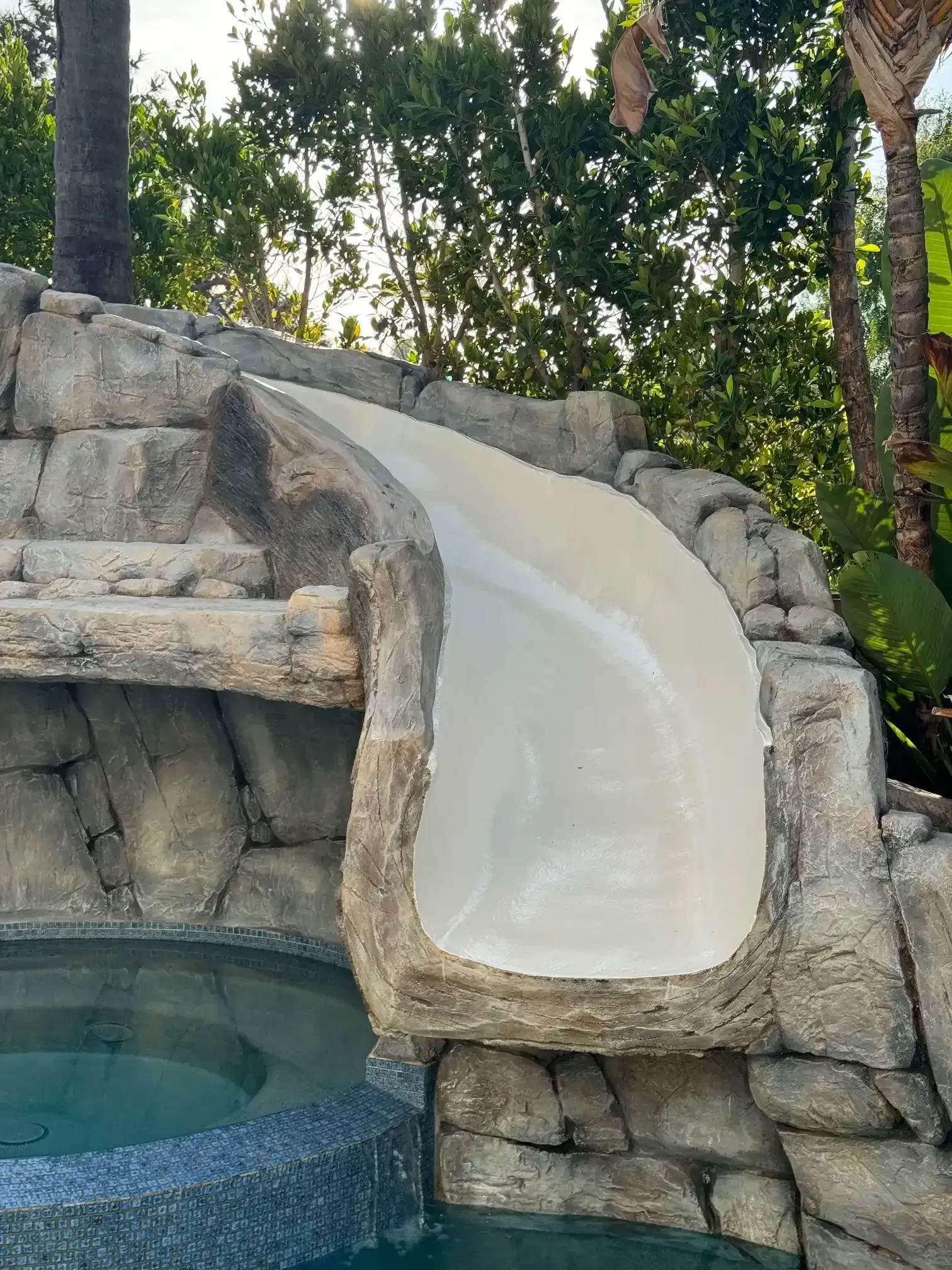 There is a water slide in the middle of a pool.