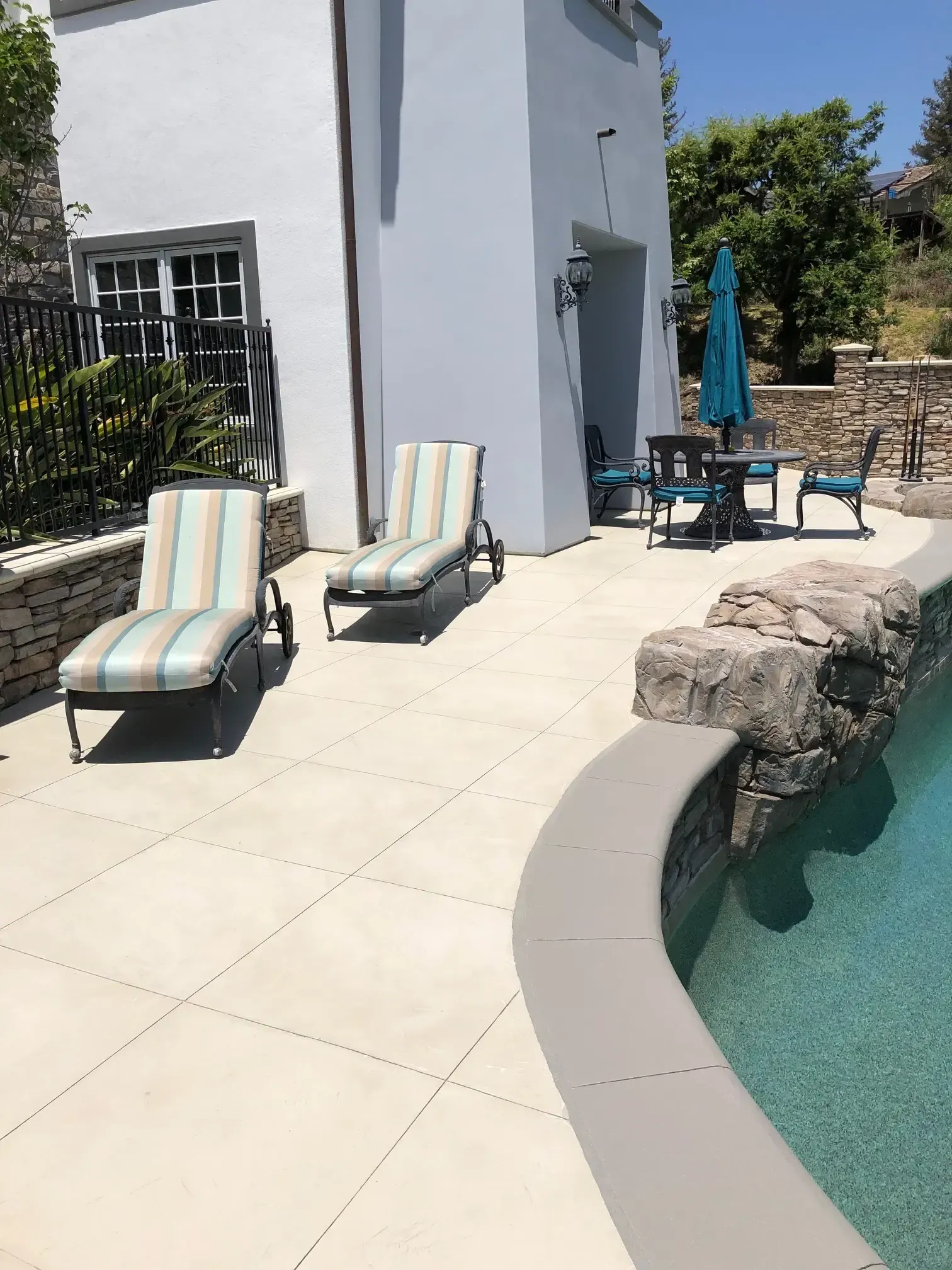 A patio with chairs and umbrellas next to a pool