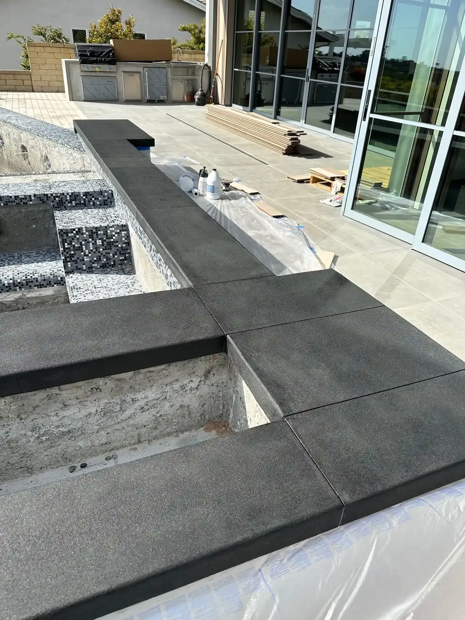 A patio with a staircase and a pool in the background.