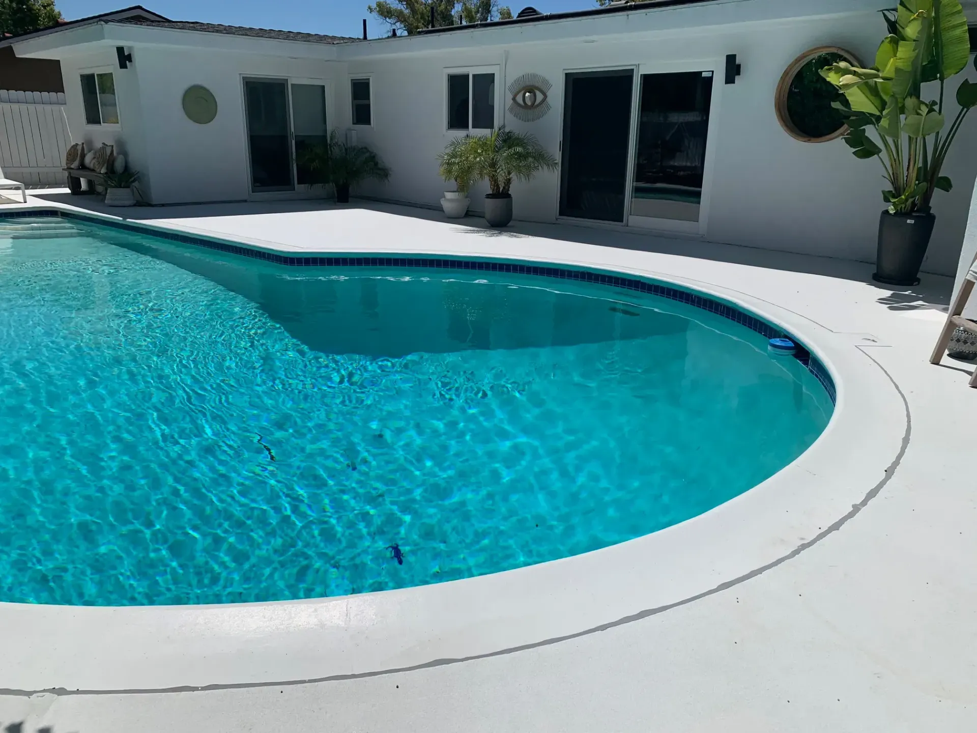 A large swimming pool in front of a white house