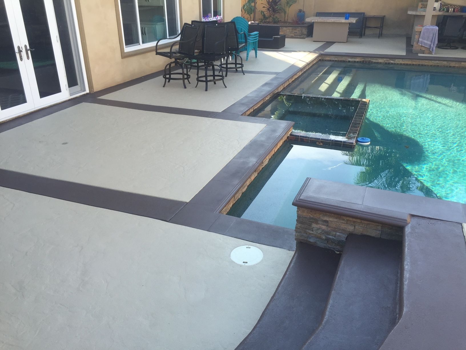 A patio with a table and chairs next to a swimming pool