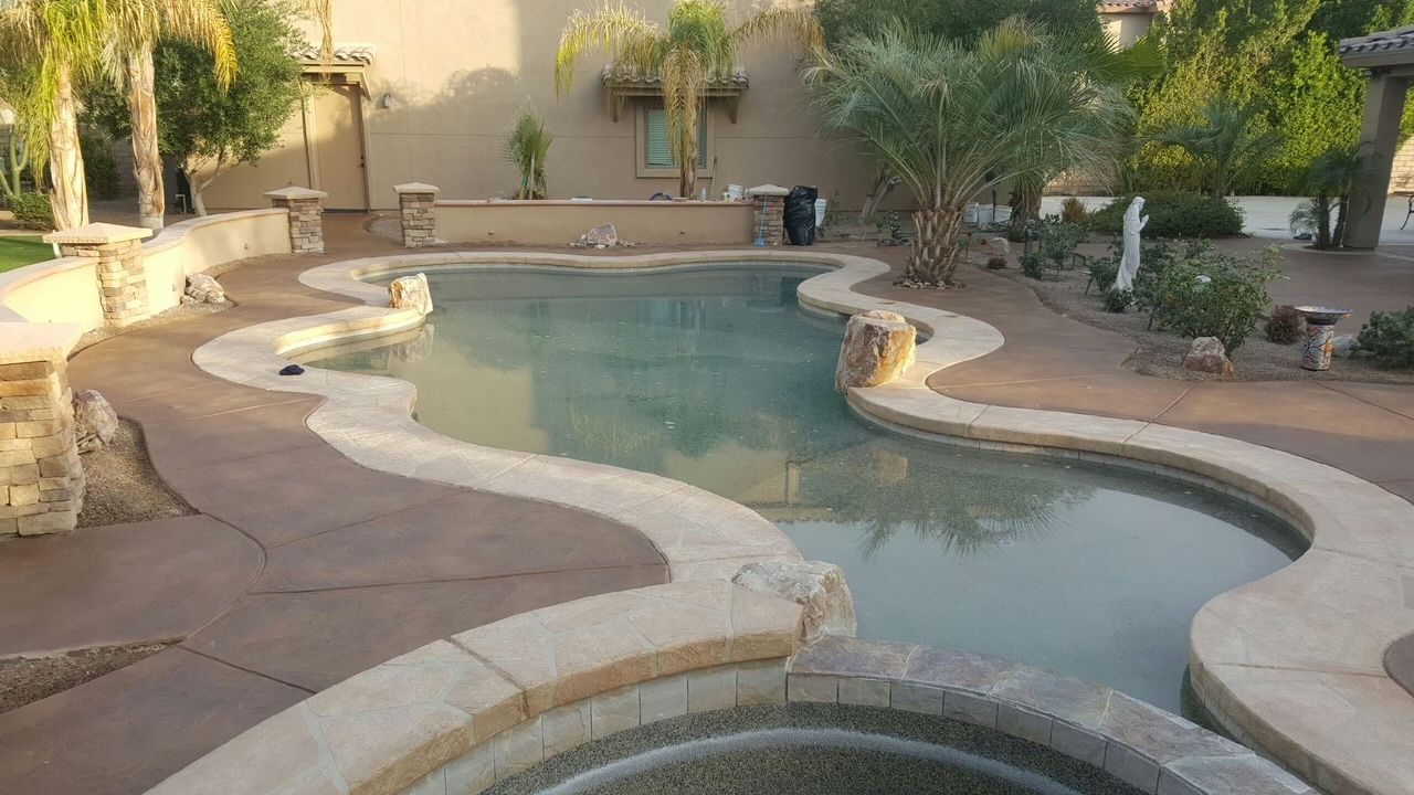 A large swimming pool with a hot tub in the backyard of a house.