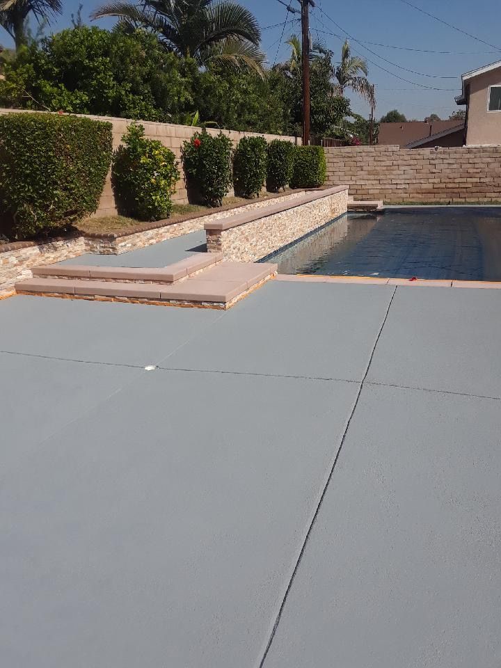 A swimming pool with a concrete deck in front of it.