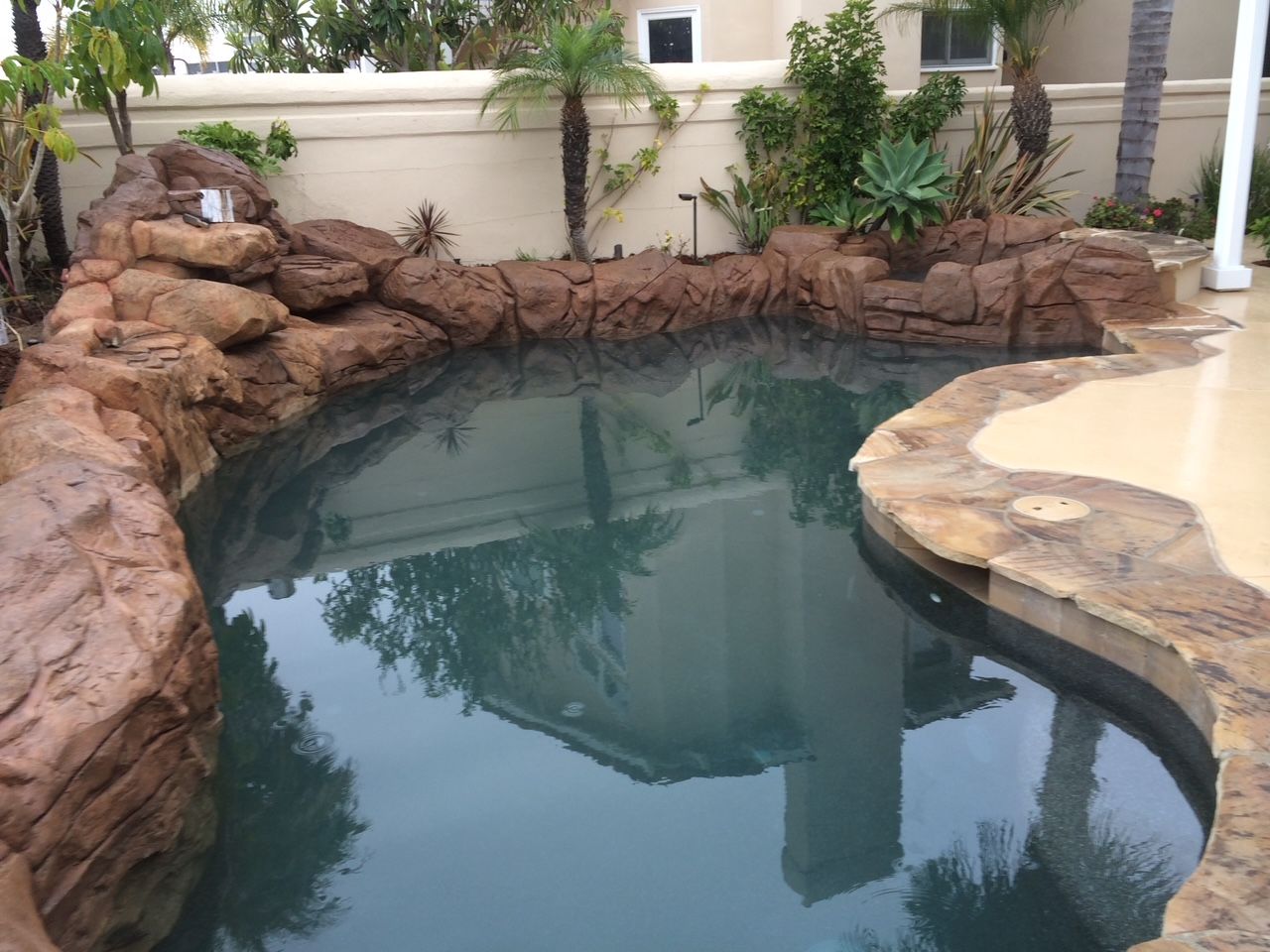 A large swimming pool with a house in the background