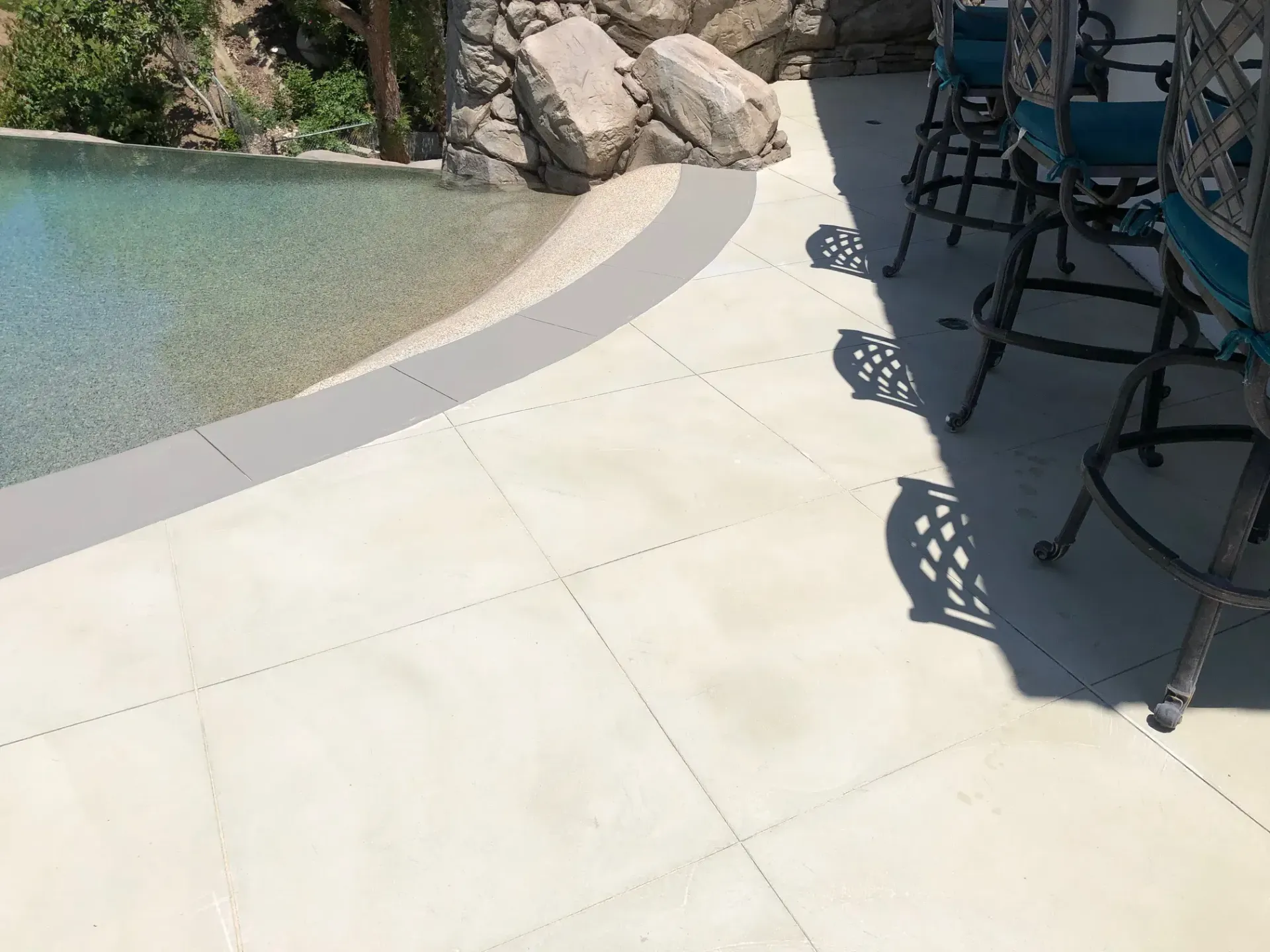 A patio with a table and chairs next to a pool.