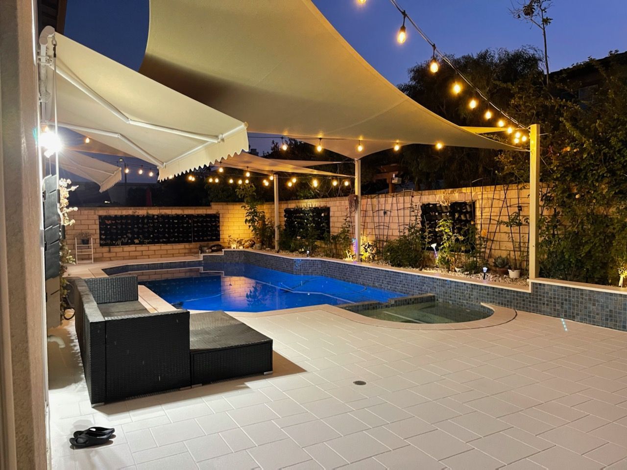 A large swimming pool is surrounded by umbrellas and lights.