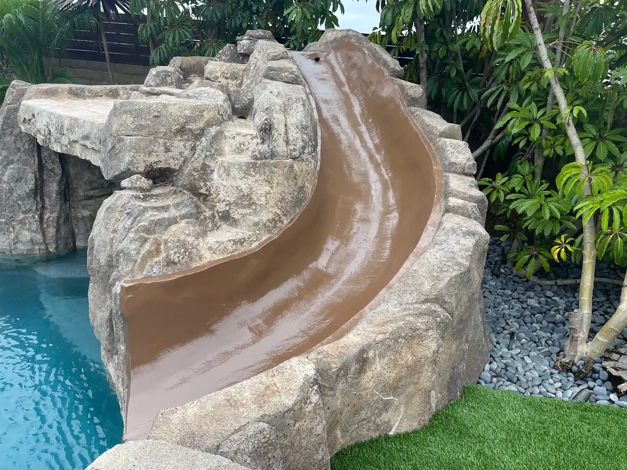 There is a water slide in the middle of a swimming pool.