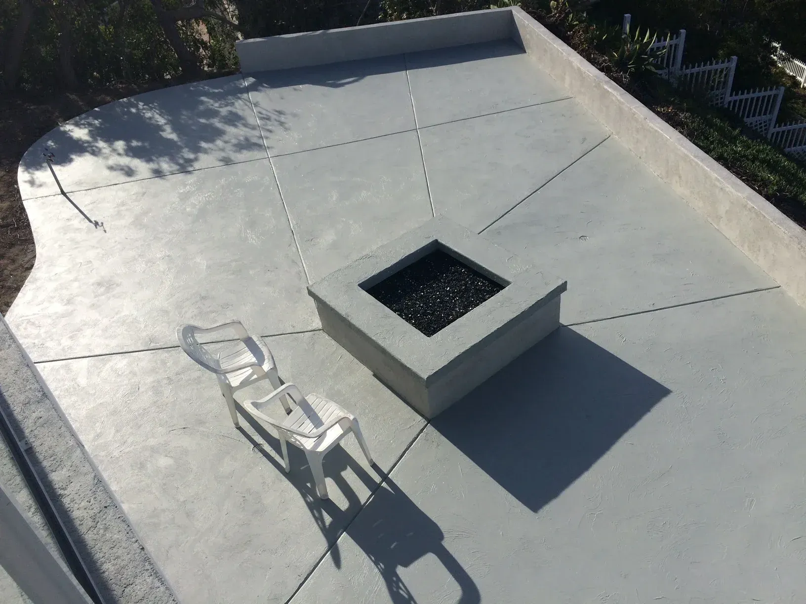 A concrete patio with a fire pit and chairs