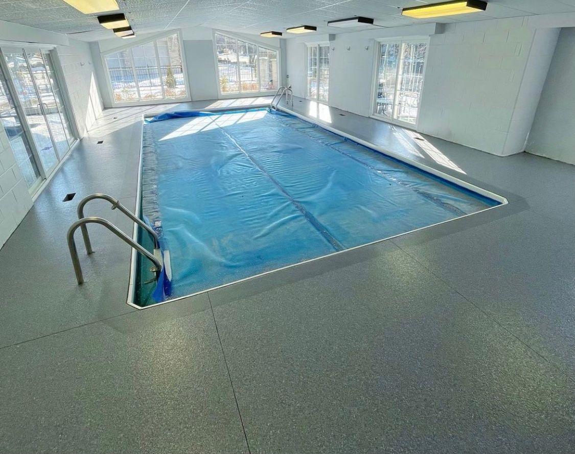 An indoor swimming pool with a blue cover and stairs