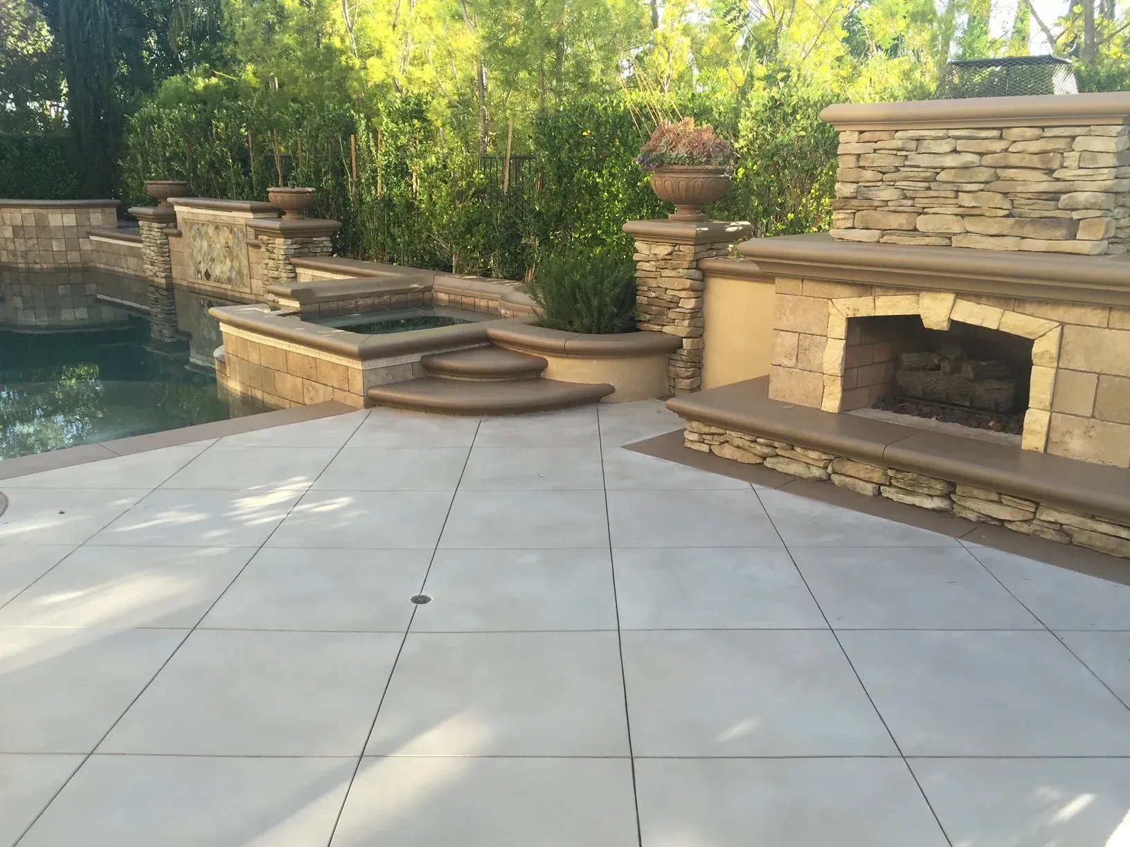 A patio with a fireplace and a pool in the background