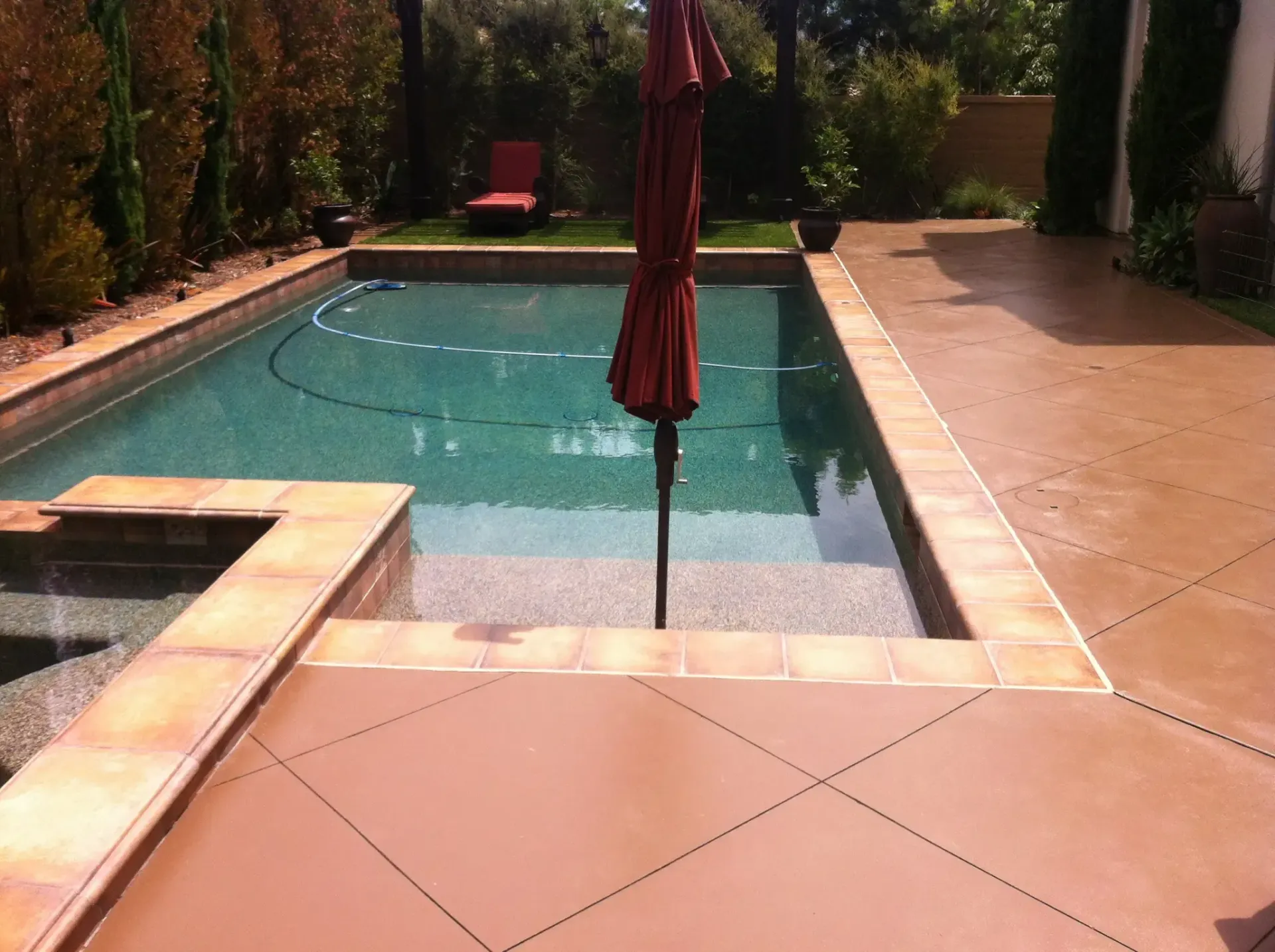 A large swimming pool with a red umbrella in the middle