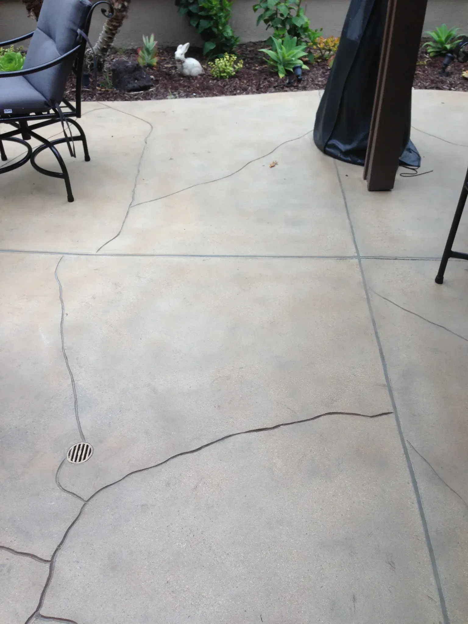 A cracked concrete patio with a chair and table